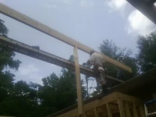 Carpenter setting a ridge beam over a new addition frame — Ice Dam Removal by Roofing Brothers in Morganville