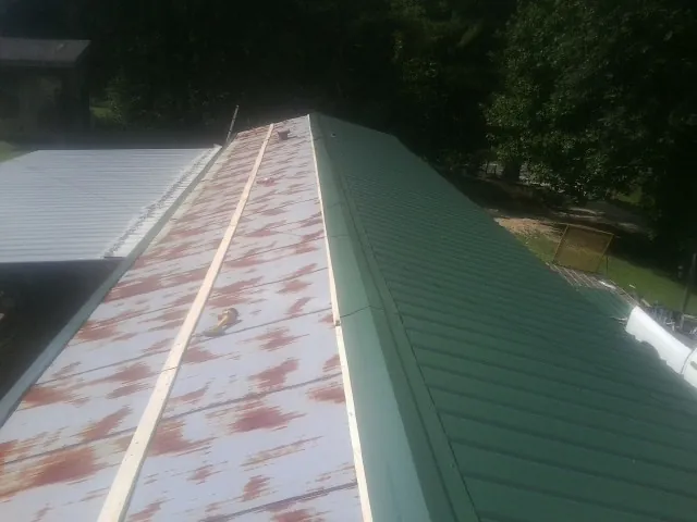 Old rusted panels beside newly installed green metal roofing — Wind Damage Roof Repair by Roofing Brothers in Morganville