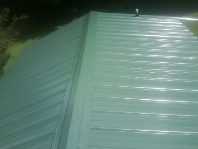 New green metal panels meeting at the ridge of a roof — Flat Roof Repair work by our crew in Morganville