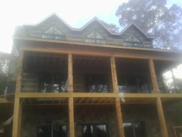 Dormers and porch framing on a large log home under construction — Roof Coating work by our crew in Morganville