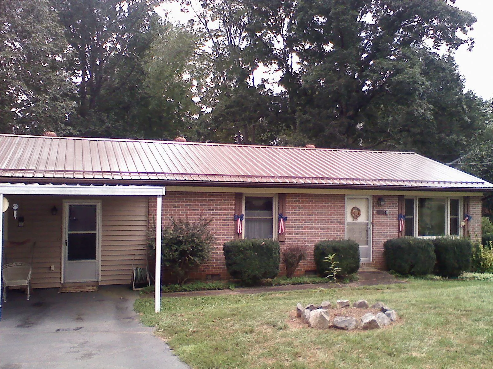 Bronze metal roof and carport on a brick ranch home — Roof Repair work by our crew in Morganville